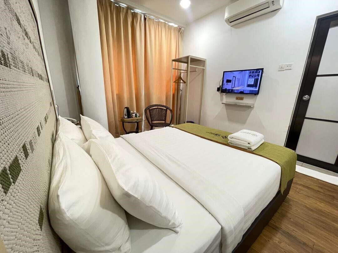 A hotel room with a bed, a television mounted on the wall, a chair, and a small table.