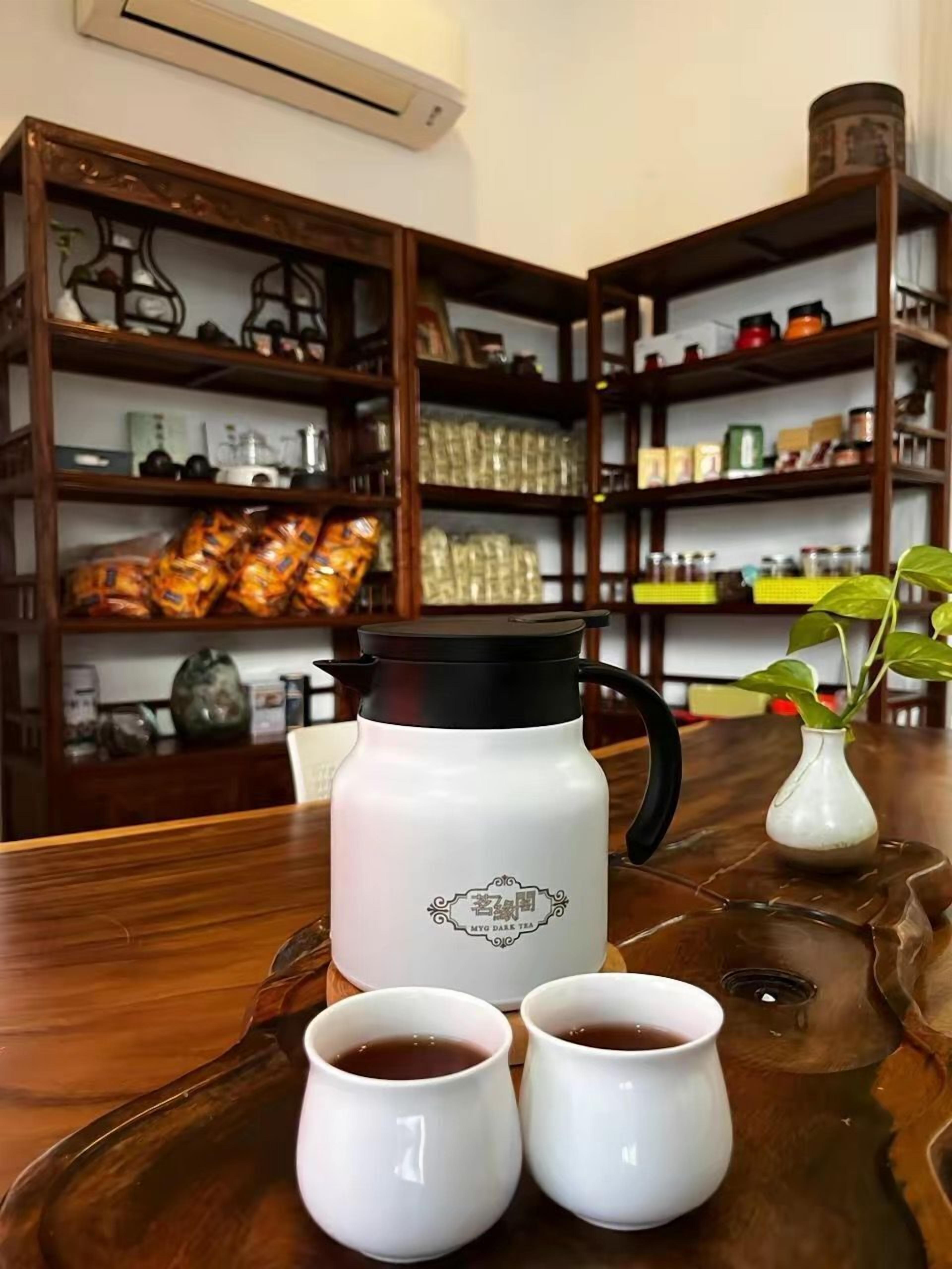 A wooden table with a white teapot and two white cups on a tray.