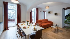 Un comedor moderno con una mesa blanca preparada para el desayuno, un sofá rojo y una pequeña mesita auxiliar.