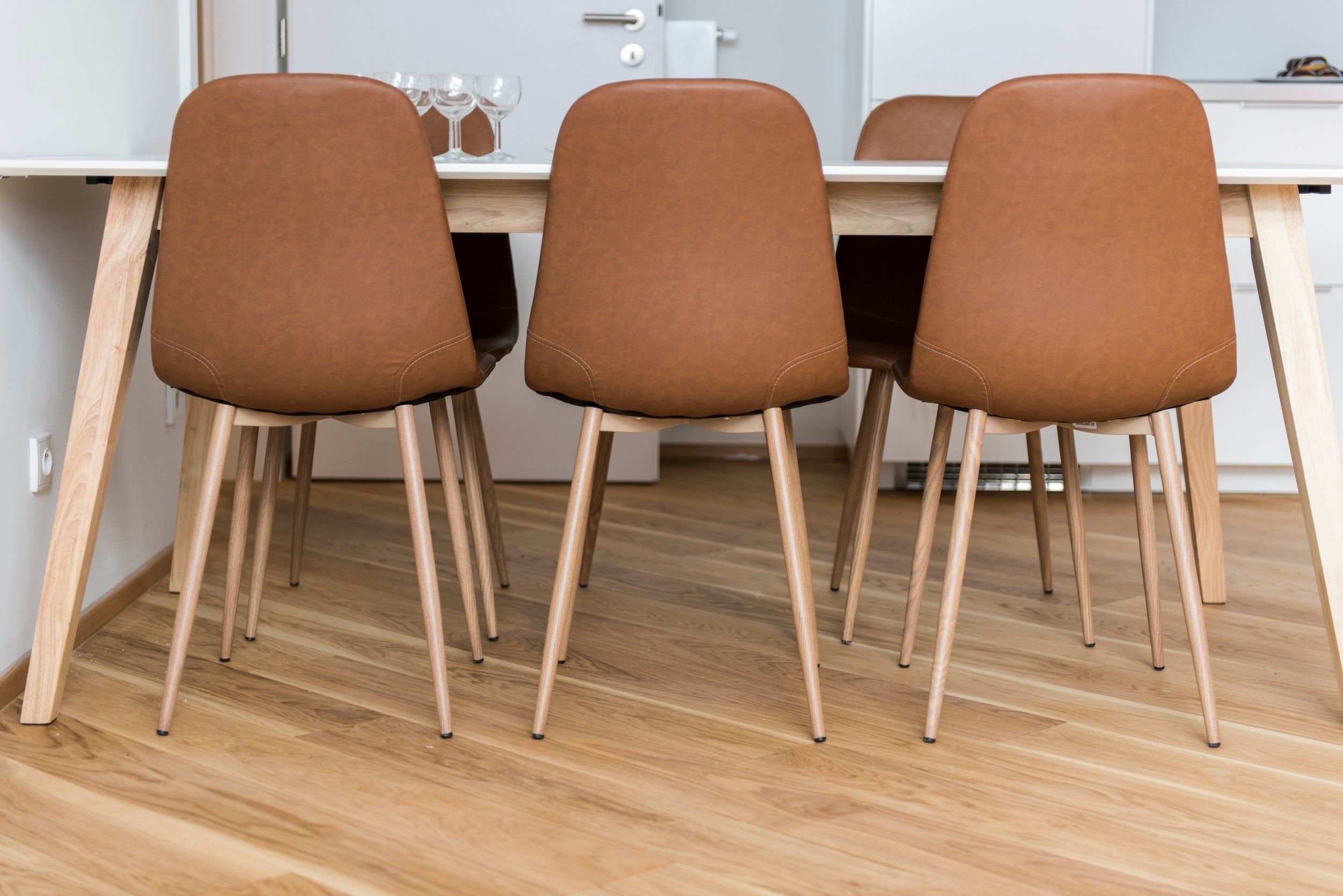 A dining area with a wooden table and four brown chairs with wooden legs.