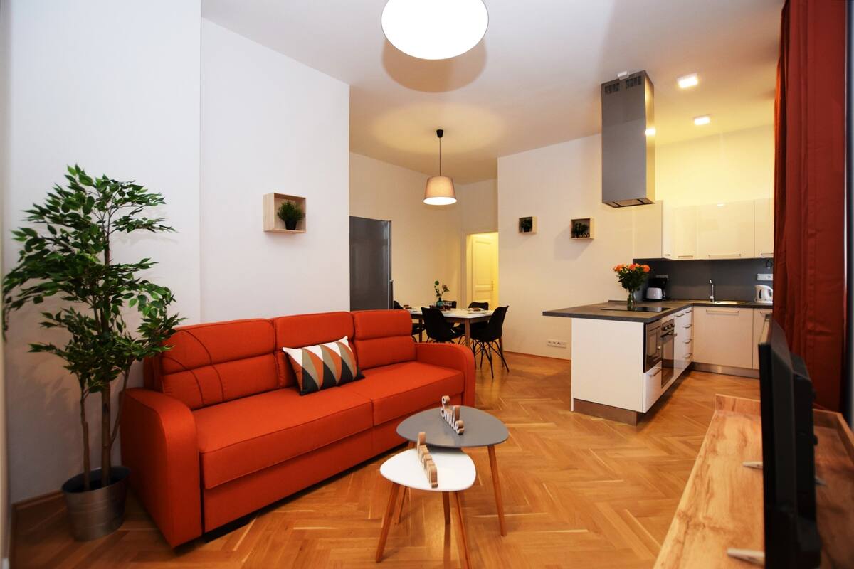 Um espaço de estar compacto com um sofá vermelho, uma mesa de jantar e uma cozinha.