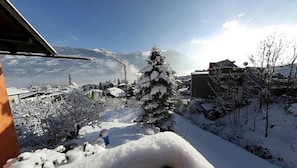 Un paisaje nevado con un árbol cubierto de nieve y edificios al fondo.