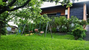 Un patio trasero con un columpio, una escalera y una casa al fondo.