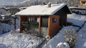 Una casa de dos pisos con techo nevado y un pequeño porche delantero.