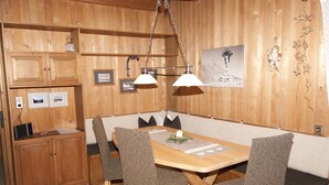 Un comedor con paneles de madera, un banco, dos lámparas colgantes e imágenes enmarcadas en la pared.