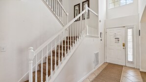 A staircase with white railings and a beige carpet leading to a door with a window above it.