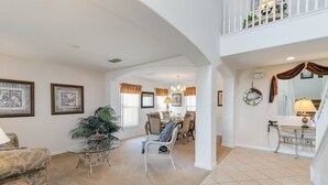 A spacious living room with a dining area, a staircase, and a balcony.