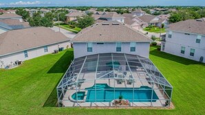 A residential area with a house featuring a large glass-enclosed swimming pool.