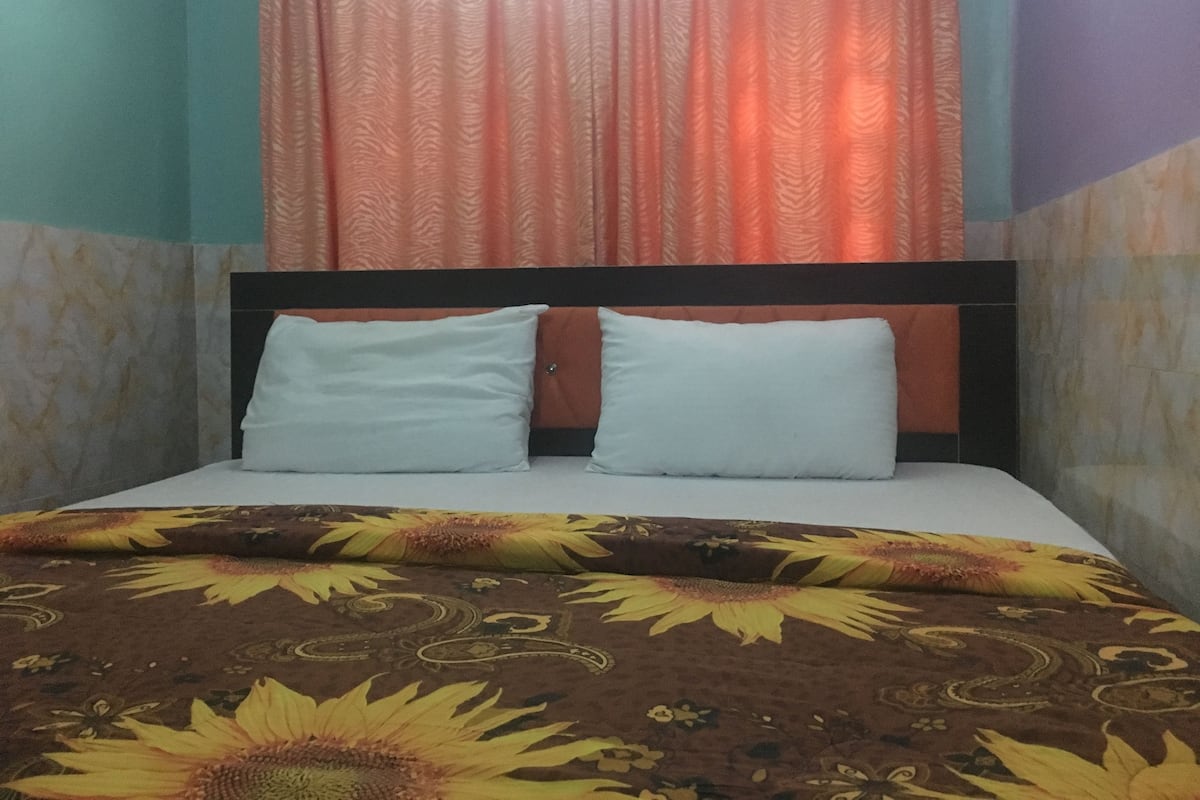 A bed with a floral bedspread, two pillows, and a headboard.