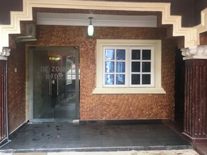 A hotel entrance with a glass door, a window with six panes, and a decorative ceiling light. - De Zone Hotel (Lagos)