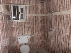 A small bathroom with a toilet, a shower, and a window. - De Zone Hotel (Lagos)