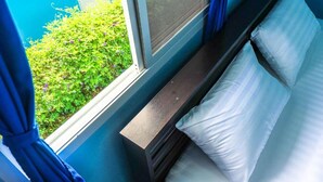 Un dormitorio con ventana, mesita de noche y cama.
