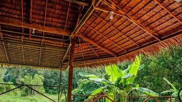 Una construcción con techo de paja y vistas de vegetación exuberante.