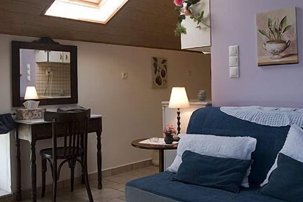Ein gemütliches Zimmer mit einem Holztisch, einem blauen Sofa und einem kleinen Beistelltisch mit einer Lampe.