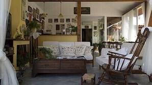 A cozy room with a wooden ceiling, a sofa, a wooden chair, and a small table.