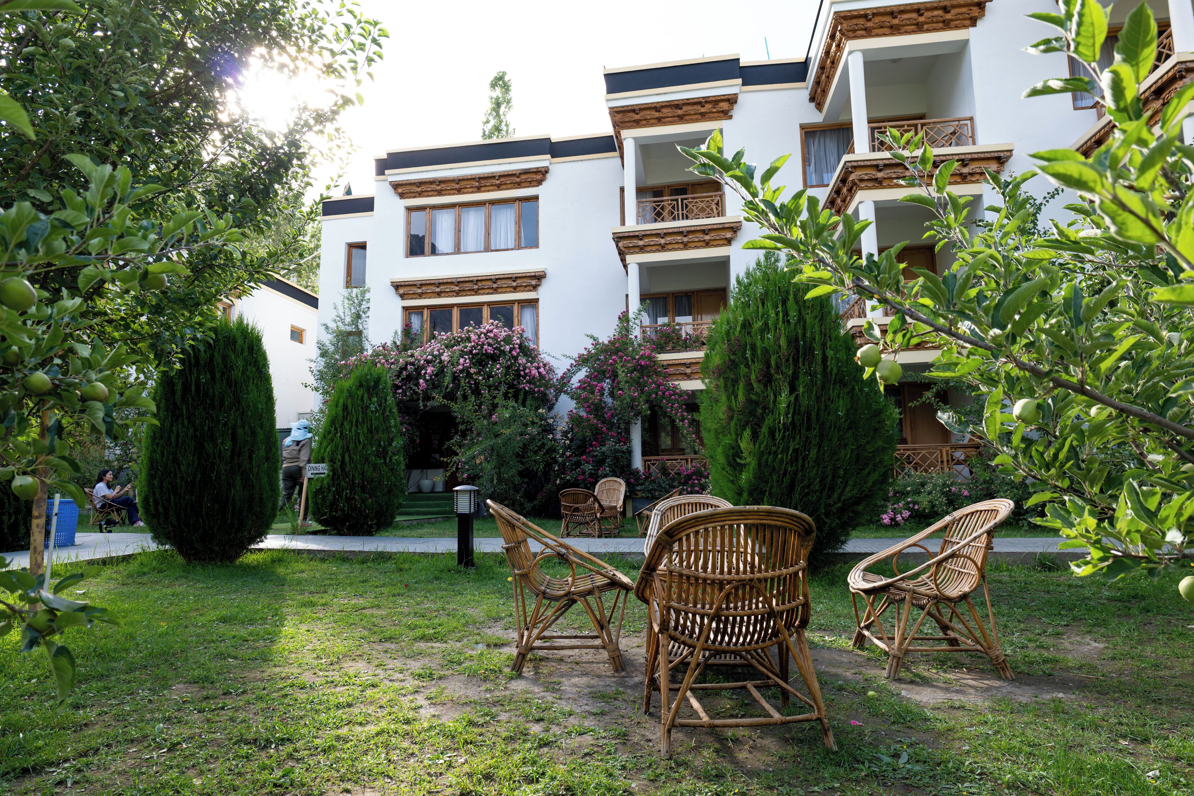 Un patio con muebles de mimbre, un césped cuidado y un edificio con balcones y ventanas.