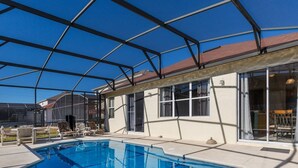 A swimming pool with a covered patio area, clear skies, and a house with large windows and a door. - Modern pool home with Game Room, 2 en suites and just 15 minutes to Theme Parks! (Davenport)