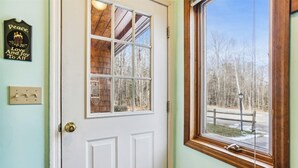 Eine weiße Tür mit einem Fenster darüber, einem Lichtschalter und einem an der Wand befestigten Schild mit einer Kerze und Text.