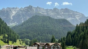 Un pueblo de montaña con edificios de estilo chalete tradicional, un valle boscoso y montañas escarpadas al fondo.