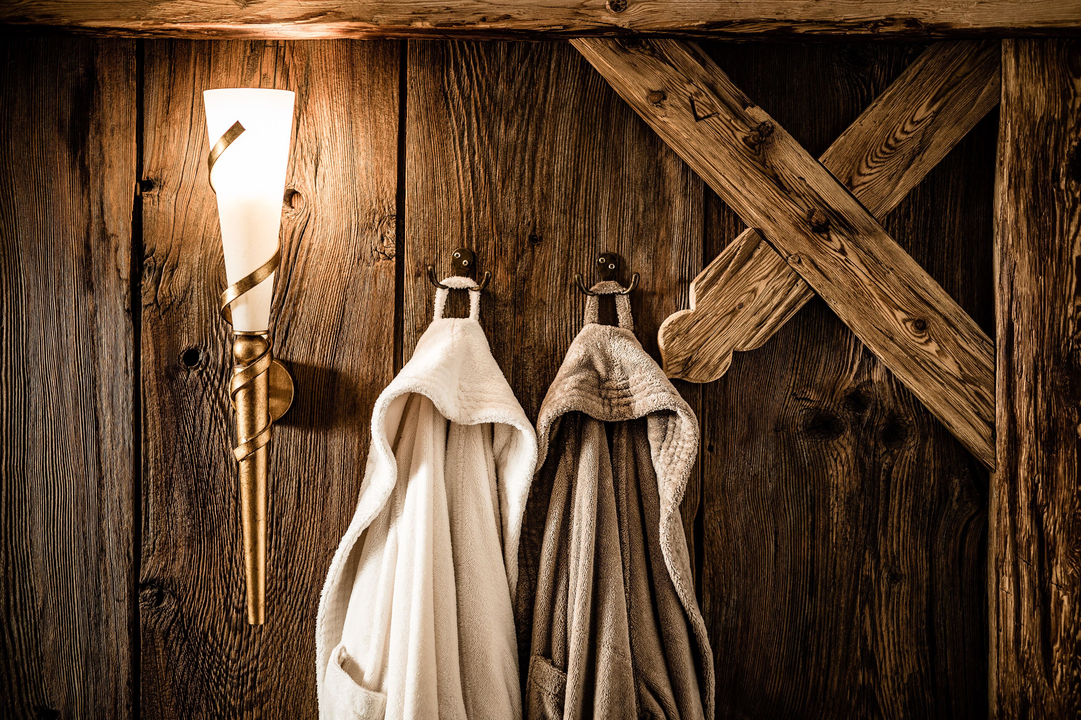A rustic wooden wall with a wall-mounted light fixture and two towels hanging on a rack.