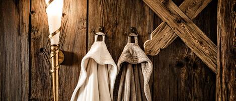 A rustic wooden wall with a wall-mounted light fixture and two towels hanging on a rack.