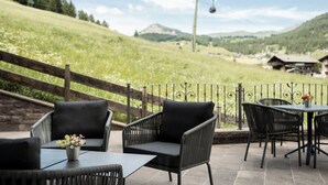 An outdoor patio with wicker furniture and a view of a mountainous landscape. - Giardin Boutique Hotel B&B (Selva di Val Gardena)