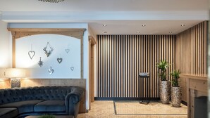 A modern living room with a dark leather sofa, a wooden coffee table, and decorative wall art. - Giardin Boutique Hotel B&B (Selva di Val Gardena)