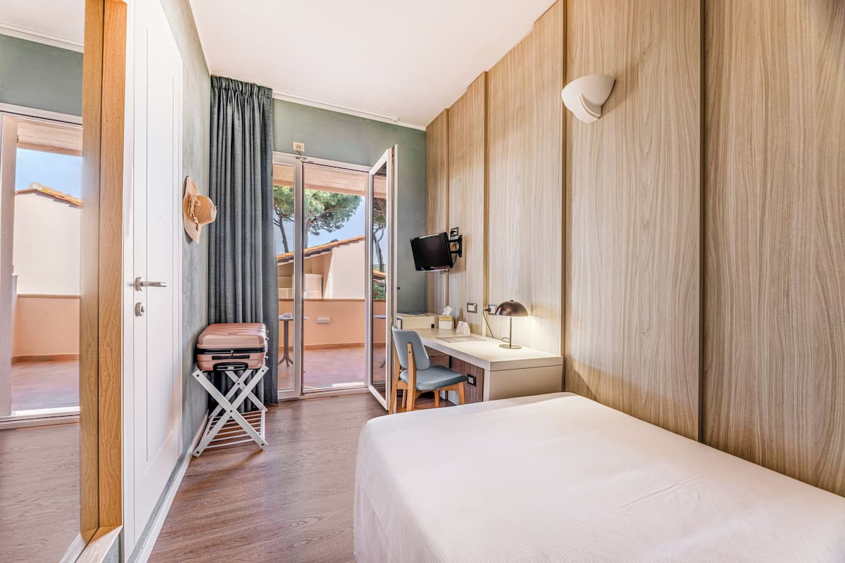 A hotel room with a bed, desk, chair, and a television.