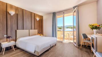 Een moderne hotelkamer met een groot bed, een bureau en een balkon met uitzicht.