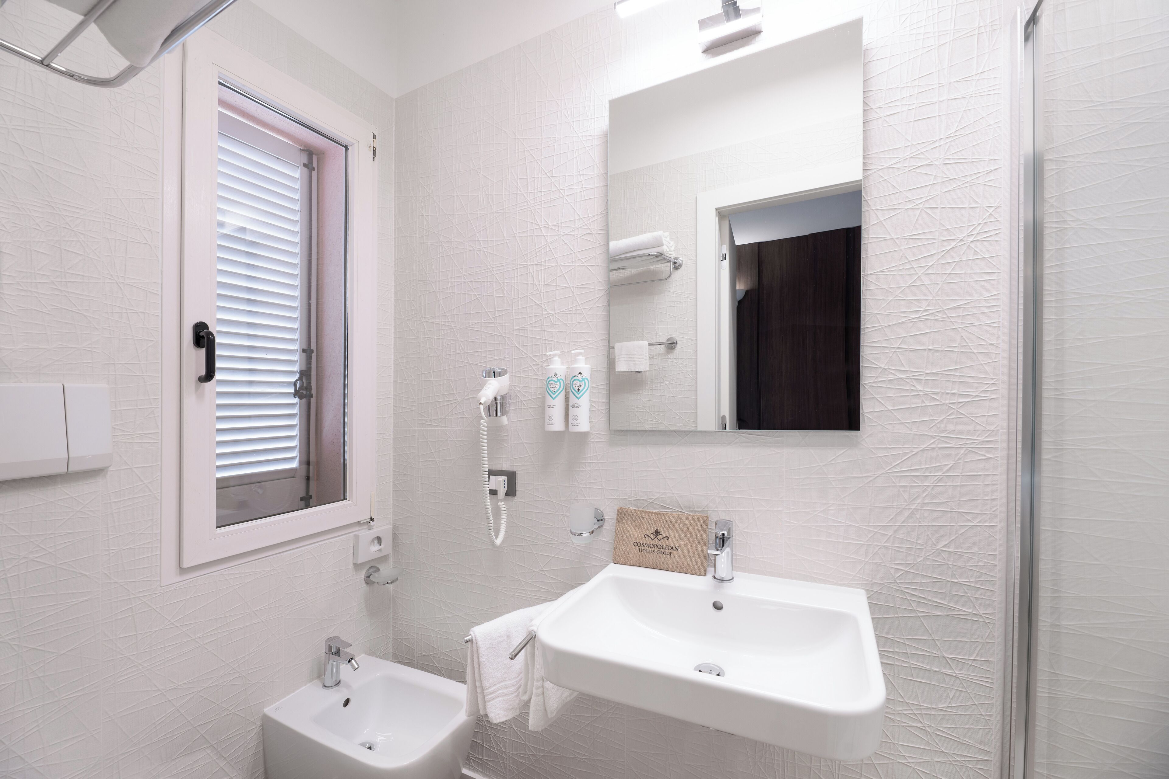 A modern bathroom with a white sink, a small vanity, a mirror, and a shower area.