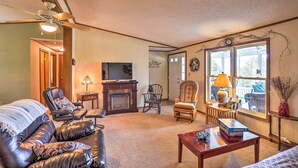A cozy living room with a leather sofa, a wooden coffee table, and a fireplace. - Finger Lakes Retreat w/ Sunroom, Fire Pit & BBQ! (Himrod)