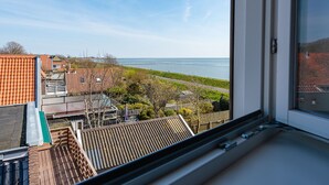 A view from a window overlooking a coastal area with terraced houses and a clear sky.