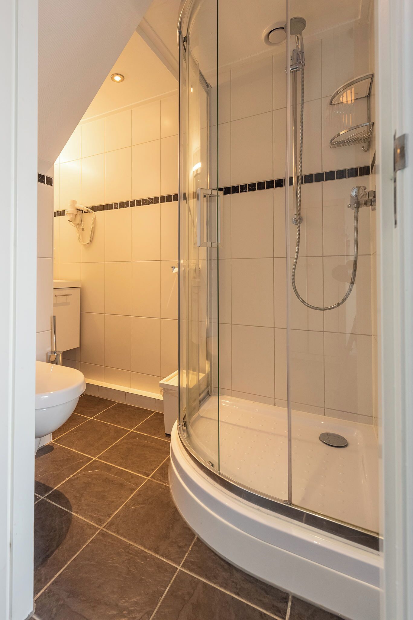A modern bathroom with a glass-enclosed shower, a toilet, and a bathtub.