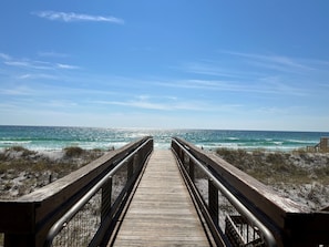 Walk along the beachside boardwalk, offering a serene view of the ocean and sandy shoreline.