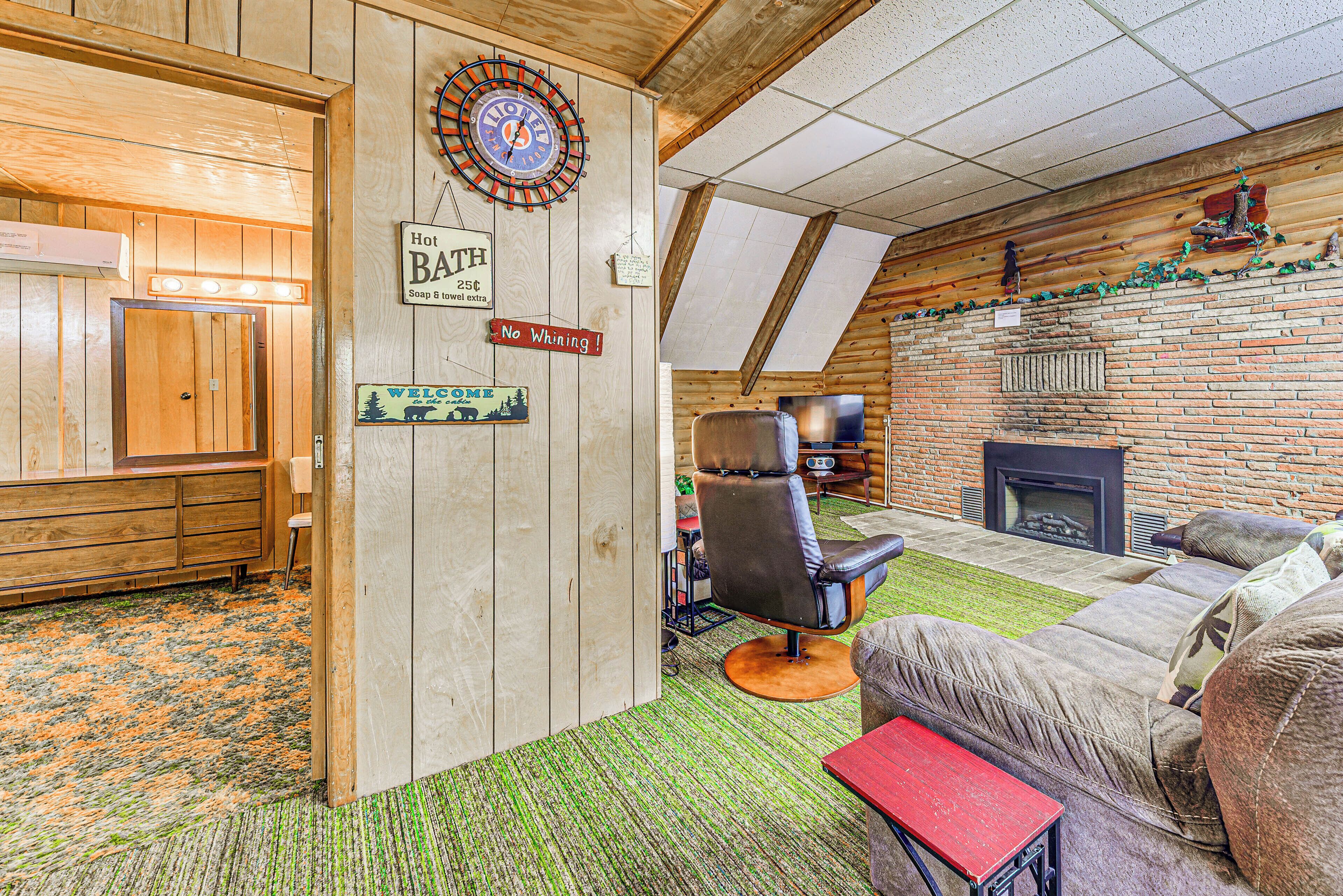 A rustic interior with a wooden wall, a dartboard, a fireplace, and a leather chair.