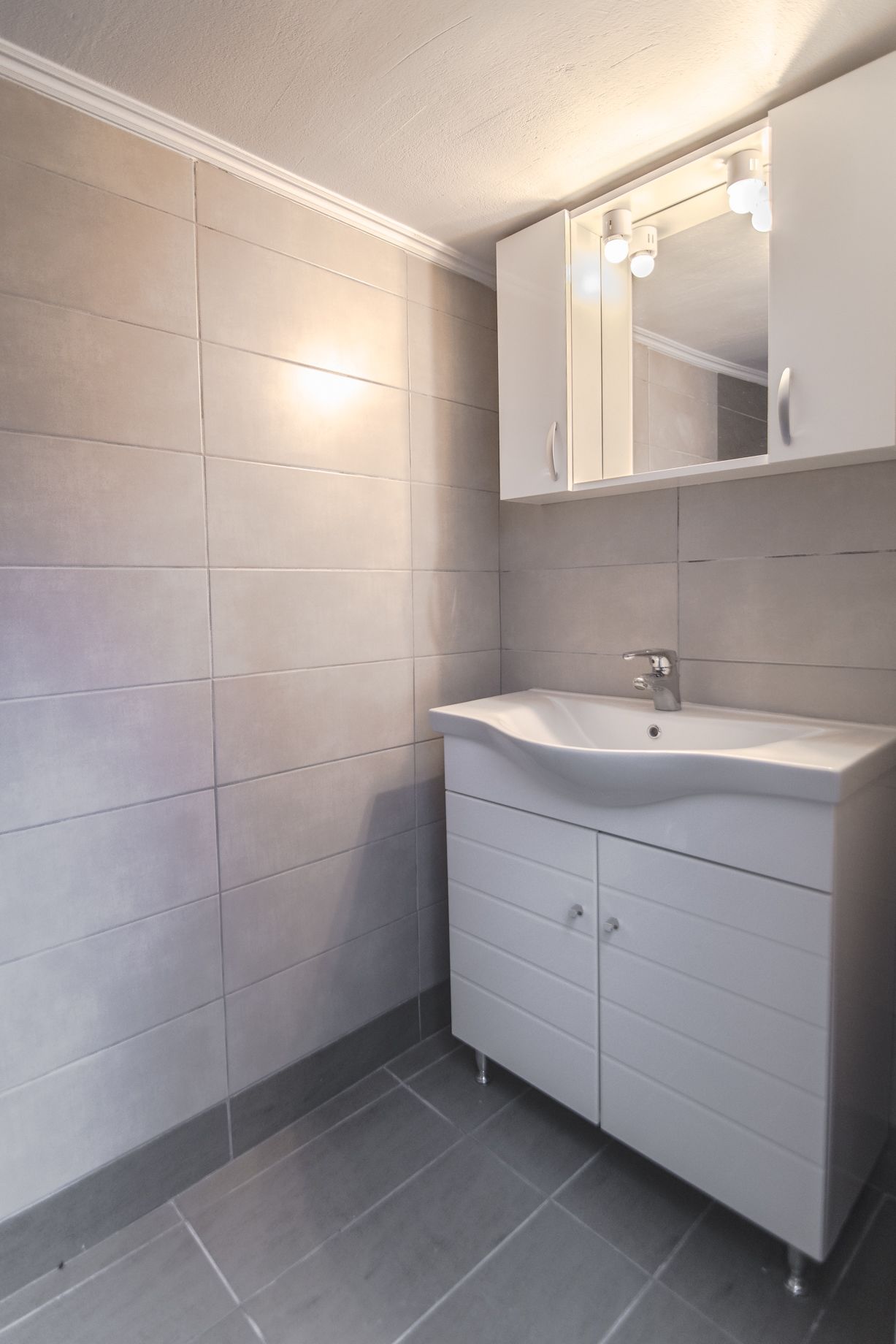 Un baño con tocador blanco, espejo y lavamanos.