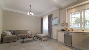 A modern living room with a sofa, coffee table, and a TV mounted on the wall. - Down Town Modern Apartments (Athens)