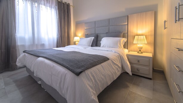 A modern hotel room with a large bed, two bedside tables with lamps, a wooden headboard, and a wardrobe. - Down Town Modern Apartments (Athens)
