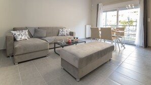 A modern living room with a sofa, ottoman, and a dining area with chairs and a table. - Down Town Modern Apartments (Athens)