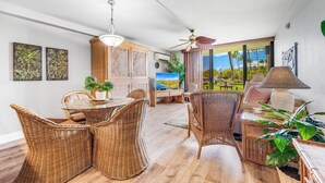 A spacious living area with wicker furniture, a television, and a view of the outdoors.