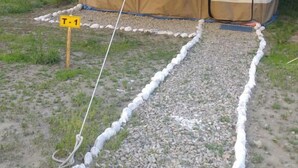 A tent with a beige and white color scheme, a gravel path leading to it, and a sign labeled "T-1". - Jispa Journeys - Campsite (Lahul)