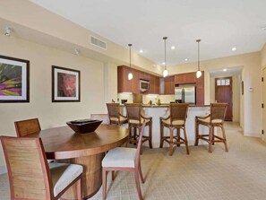 A modern kitchen with wooden cabinets, a central island, and pendant lighting.