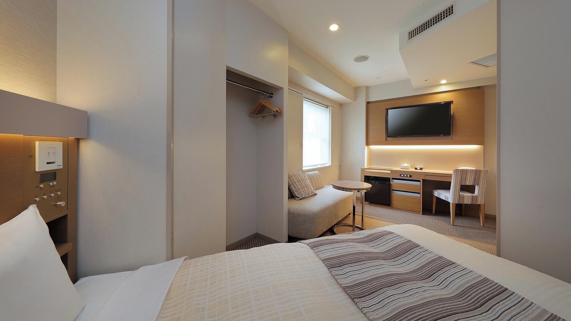 A hotel room with a bed, a desk, a chair, a television, and a bathroom.