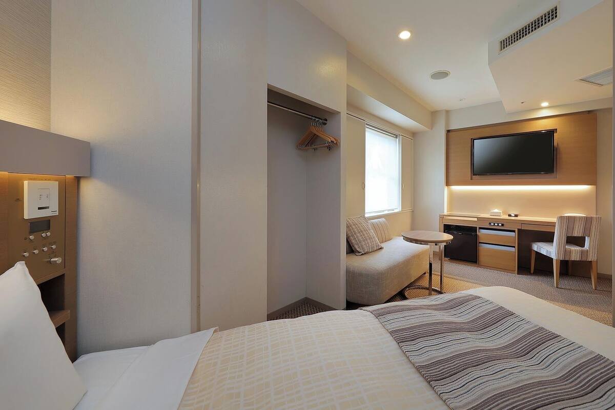 A hotel room with a bed, a desk, a chair, a television, and a bathroom.