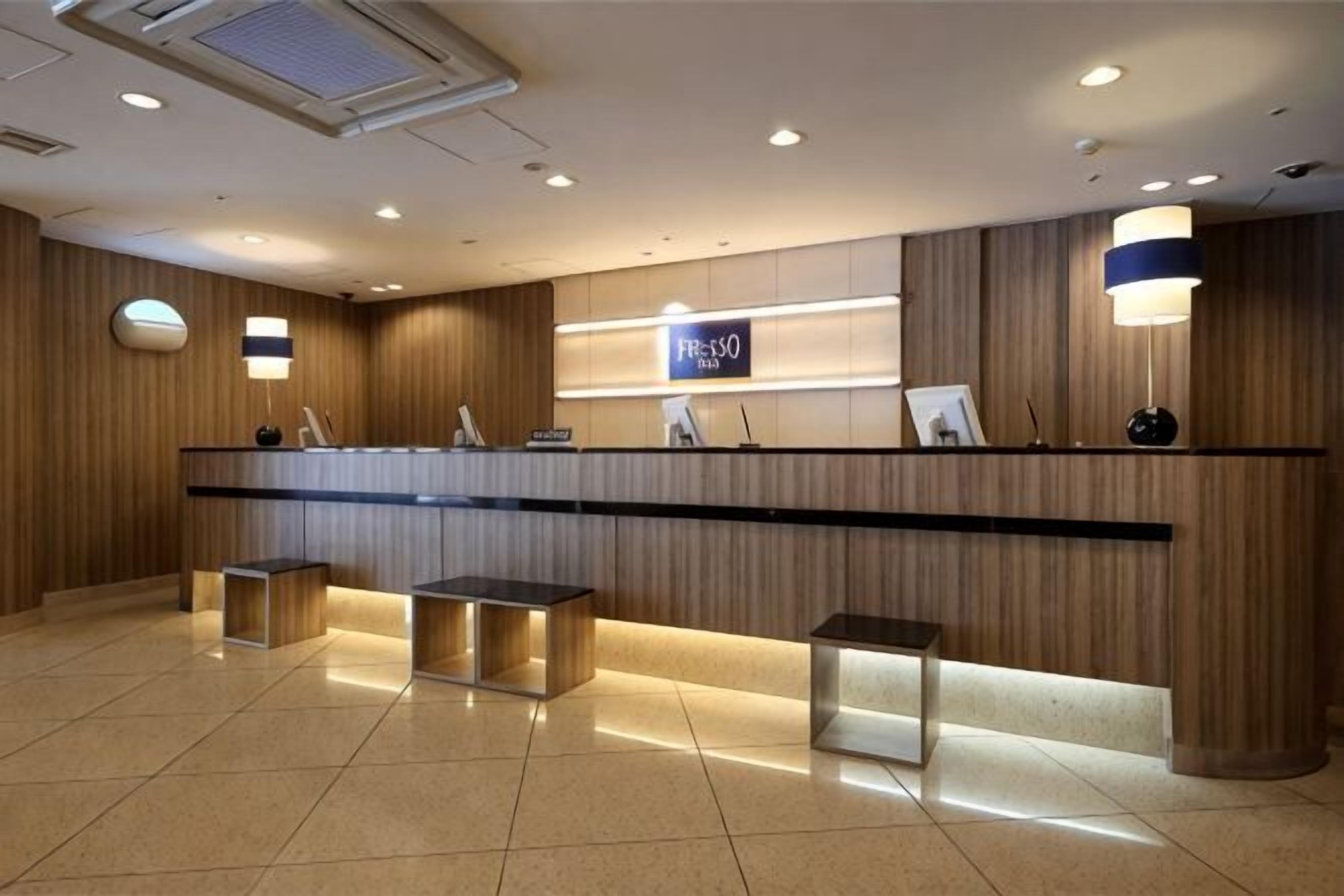 A reception area with a wooden reception desk, a digital display, and a seating area with cushioned benches.