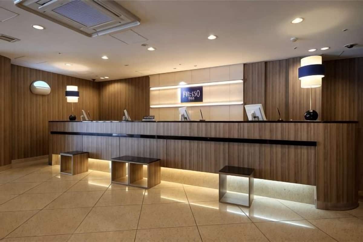 A reception area with a wooden reception desk, a digital display, and a seating area with cushioned benches.