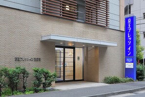 A hotel entrance with a modern design, featuring a brick facade and a prominent blue sign indicating the name and brand. - Keio Presso Inn Gotanda (Tokyo)