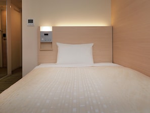 Ein Hotelzimmer mit Bett, Kopfteil, Bedienfeld und Tür.