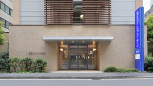 A modern building with a glass entrance, a sign indicating a business center, and a blue sign with Japanese characters. - Keio Presso Inn Gotanda (Tokyo)