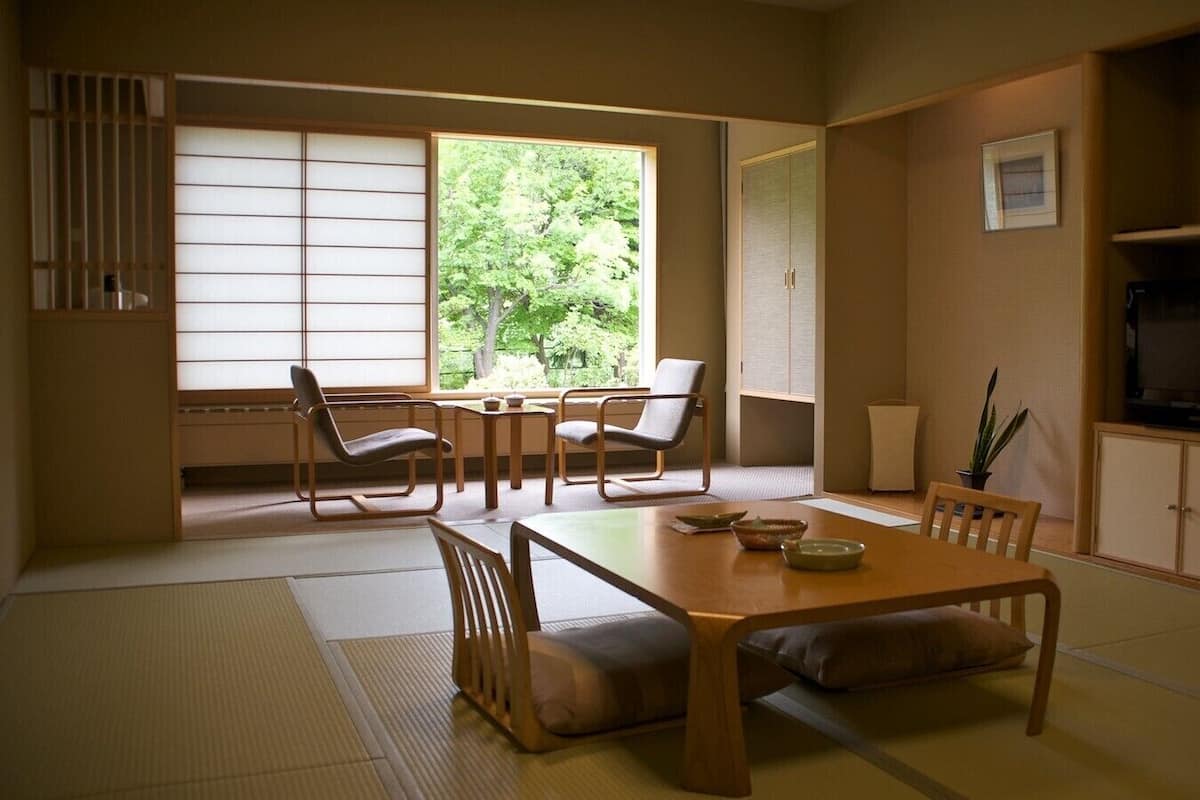 A traditional Japanese-style room with tatami flooring, a low table with cushions, and sliding doors leading to a balcony.